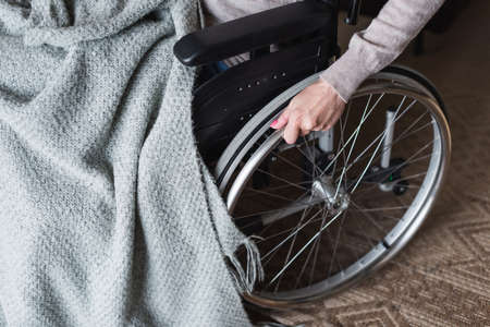 Cropped view of elderly woman holding wheel of wheelchair at homeの写真素材