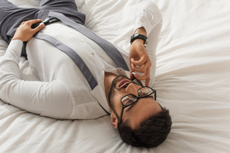 High angle view of businessman in formal wear talking on cellphone on bedの写真素材