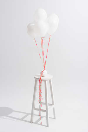 lightweight balloons above stool with ball of thread on whiteの写真素材