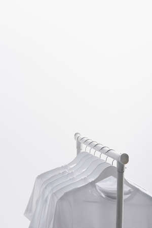trendy t-shirts hanging on clothes rack isolated on whiteの写真素材