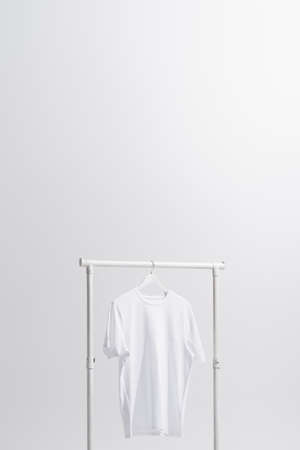 white t-shirt hanging on clothes rack isolated on gray
