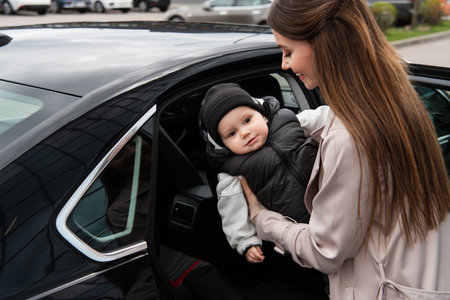 young mother putting baby boy into automobileの写真素材