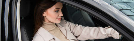 young woman smiling while driving automobile, banner
