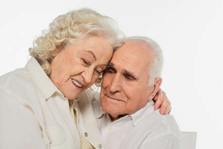 portrait of happy elderly couple gently hugging isolated on whiteの写真素材
