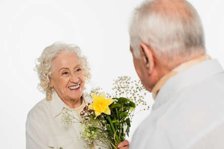 elderly man presenting bouquet of flowers to smiling wife isolated on whiteの写真素材