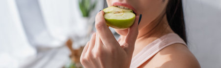 cropped view of young woman biting apple, bannerの写真素材