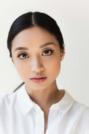 Portrait of asian woman looking at camera isolated on gray