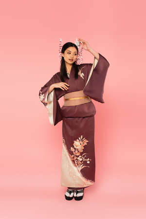 Full length of japanese woman in oriental clothes and footwear on pink backgroundの写真素材