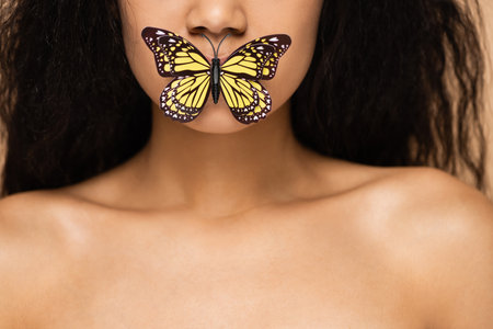 cropped view of african american young woman with butterfly on lipsの写真素材