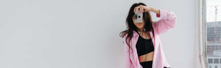 young armenian woman taking photo on digital camera on white, bannerの写真素材