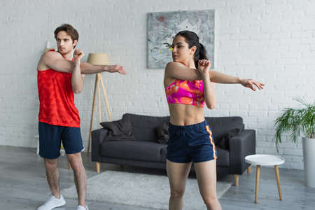 young couple in sportswear warming up before workout at homeの写真素材