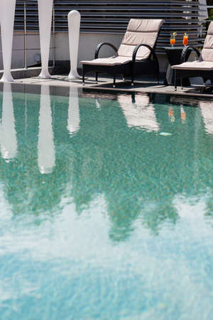 Cocktails near deck chairs and swimming pool outdoorsの写真素材