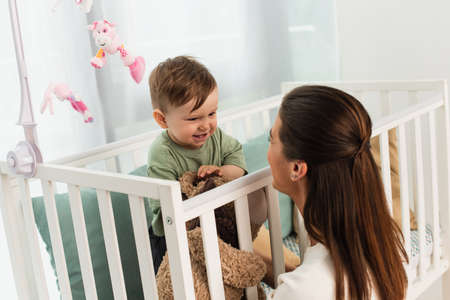 Happy kid with toy looking at mother at home