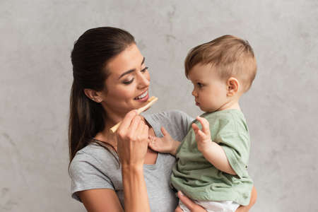 Smiling mother holding toothbrush and kid at home