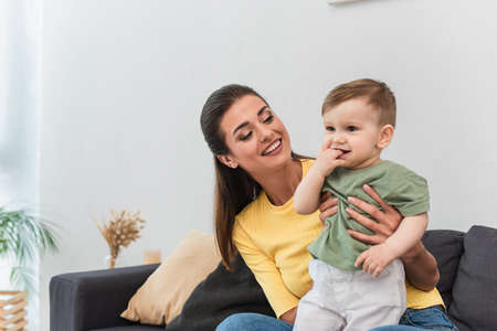 Young mother hugging cheerful son in living room