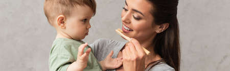 Young mother with toothbrush looking at son, bannerの写真素材