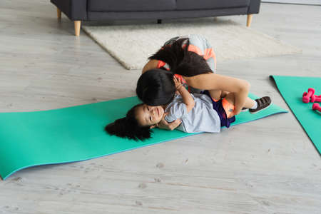 Woman kissing asian kid on fitness matの写真素材