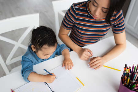Overhead view of asian child drawing near color pencils and parentの写真素材