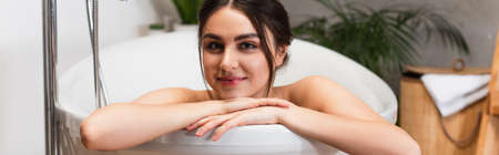 happy young woman looking at camera in bathtub, banner
