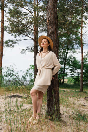 full length of smiling young woman in straw hat standing in forestの写真素材