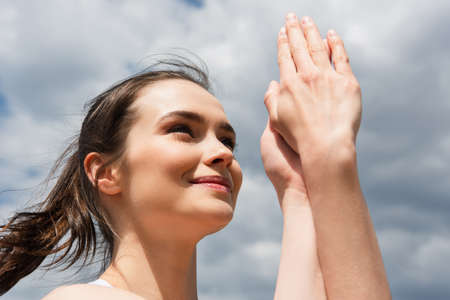 low angle view of happy woman with clenched hands against blue sky with cloudsの写真素材