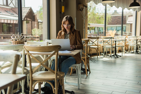 Stylish teleworker using laptop near menu in cafeの写真素材