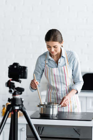 young culinary blogger preparing food in front of blurred digital cameraの写真素材