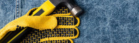 top view of hammer near yellow rubberized work glove on denim cloth, labor day concept, bannerの写真素材