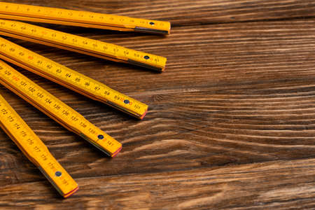 yellow folding ruler on wooden surface, labor day conceptの写真素材