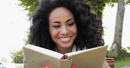 Smiling african american woman reading book in hardcover