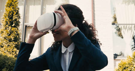 pleased african american businesswoman using vr headset outside