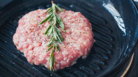 close up of mince patty with salt and rosemary branch on hot panの写真素材