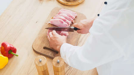 high angle view of chef cutting beef tenderloin on chopping board near bell peppersの写真素材