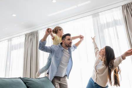 happy family imitating flying while having fun at homeの写真素材