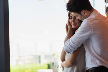 man in shirt hugging pleased woman in restaurant