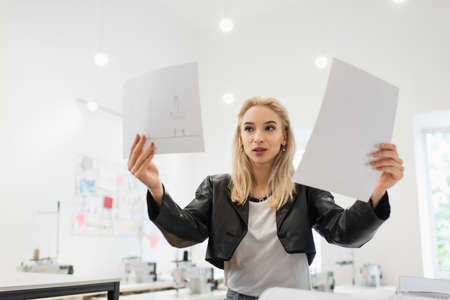 trendy fashion designer looking at drawings in tailor shop