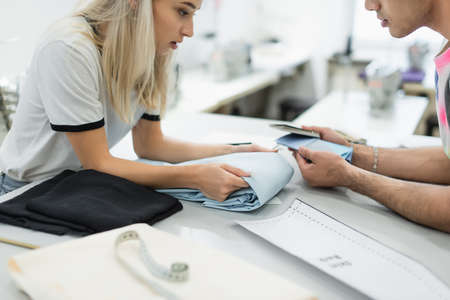 cropped view of designers looking at tissue and color palette near sewing pattern, blurred...