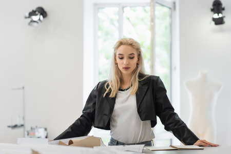 trendy fashion designer looking at sewing patterns while working in tailor shop