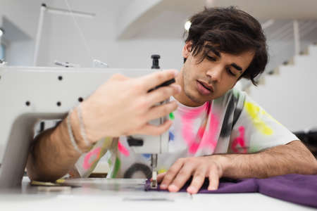 trendy tailor adjusting sewing machine while working in atelierの写真素材