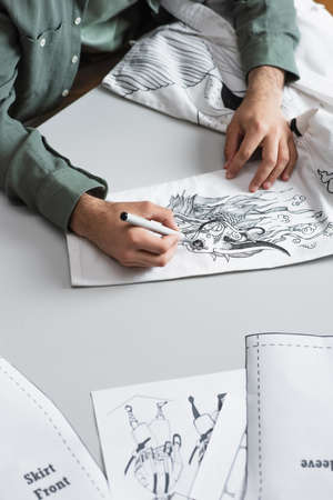 cropped view of fashion designer drawing with felt pen on kimono near sewing patternsの写真素材
