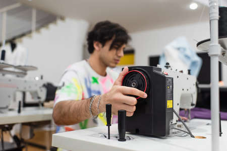 young blurred tailor regulating sewing machine in fashion workshopの写真素材