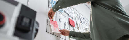 low angle view of cropped fashion designer attaching drawings on wall in atelier, bannerの写真素材