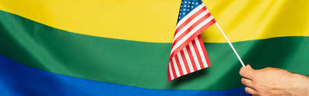 cropped view of man holding american flag against lgbt colorful background, bannerの写真素材