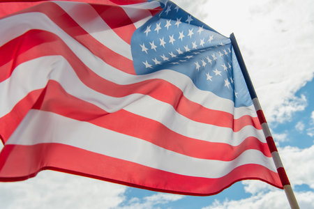 low angle view of american flag with stars and stripes against cloudy skyの写真素材