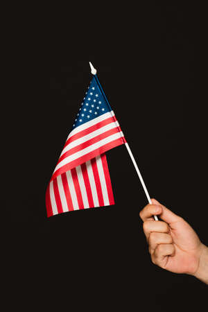 cropped view of patriotic man holding flag of america isolated on blackの写真素材