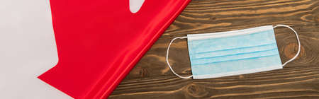 top view of canadian flag and medical mask on wooden surface, banner