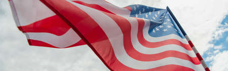 low angle view of american flag with stars and stripes against cloudy sky, bannerの写真素材