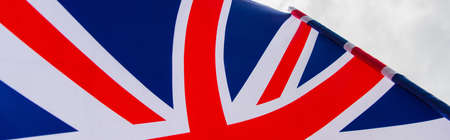 close up view of national flag of united kingdom with red cross against sky, bannerの写真素材