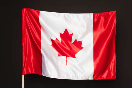 Canadian flag with red maple leaf isolated on blackの写真素材
