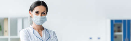 Doctor in medical mask looking at camera in clinic, bannerの写真素材